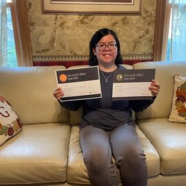 Photo of Eleni holding her certifications