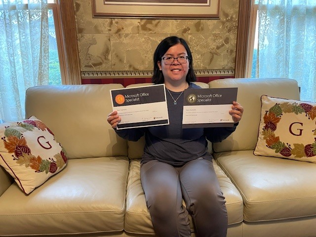 Photo of Eleni holding her certifications